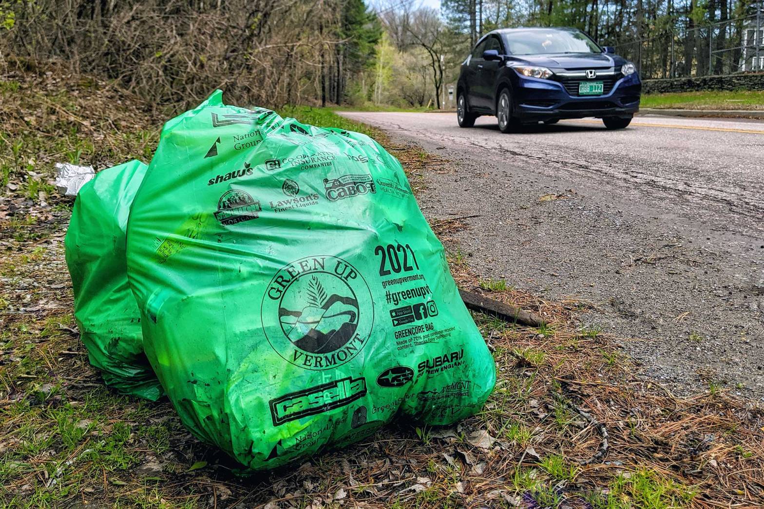 Full green trash bags on the side of a street