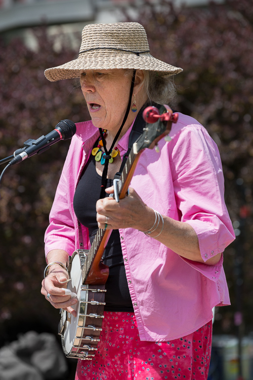 Musician sings and plays banjo outside on a sunny day